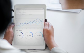 person holding tablet with graphs displayed on the screen