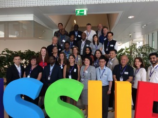 A group of adult who work for ISSUP National Chapters standing on stairs behind large letters spelling ISSUP